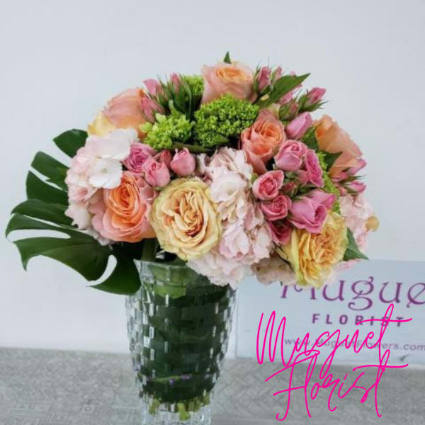 Bouquet of pastel roses and pink blooms in a clear glass vase