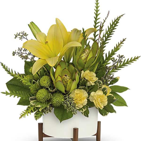 Yellow lilies and green protea in a white planter on wooden legs