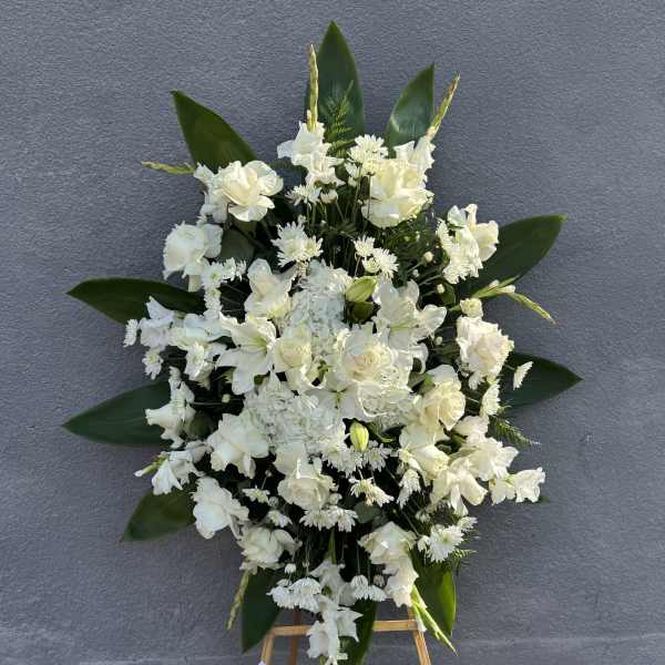 White funeral spray on an easel with a ribbon