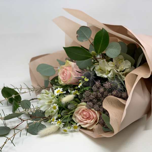 Bouquet of pink roses and white flowers wrapped in blush paper