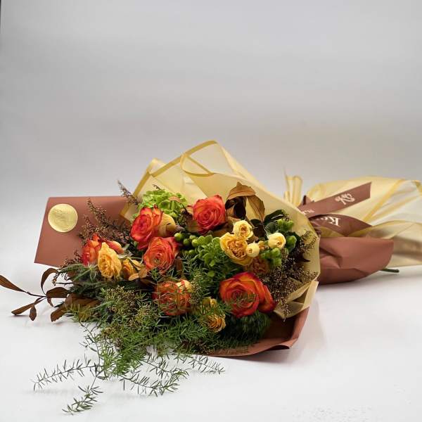 Bouquet of orange and yellow roses wrapped in tan paper