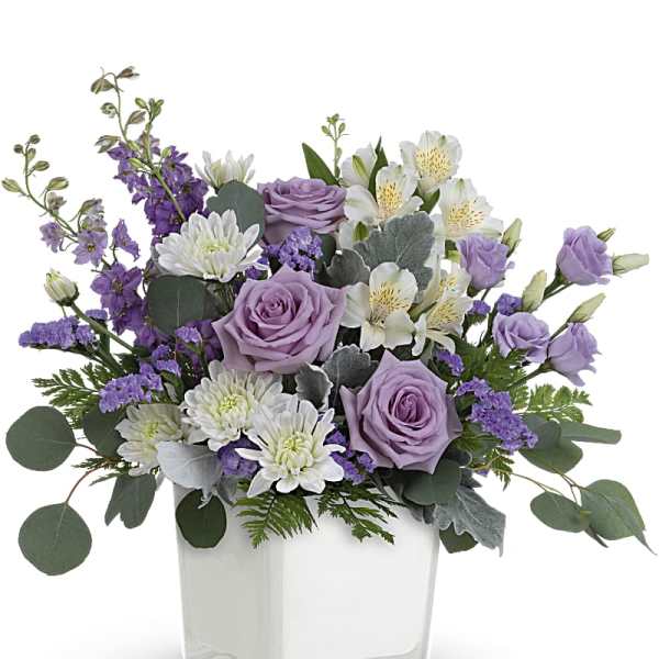 Lavender roses and white flowers in a clear square vase