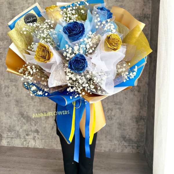 Bouquet of blue and gold roses with white baby's breath
