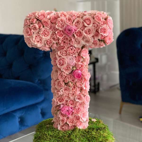 Pink rose-covered letter T on a moss base