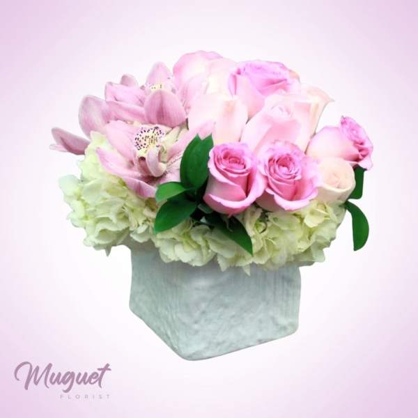 Pink roses and lilies arranged in a square vase