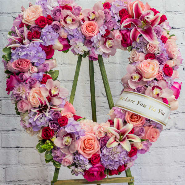 Heart-shaped floral wreath on an easel with pink, purple, and white blooms