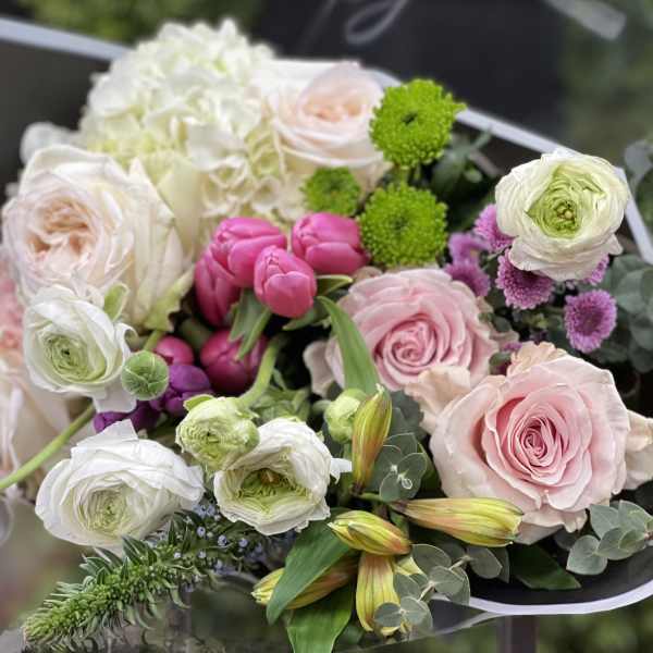 Bouquet of pink and white roses with ranunculus and green accents