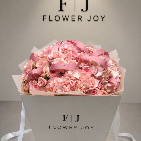Pink rose and hydrangea bouquet in a white gift box with ribbon