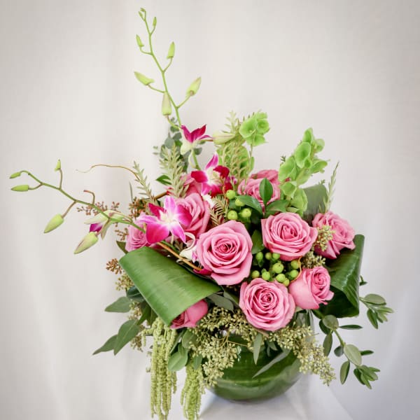 Pink roses and orchids arranged in a green vase