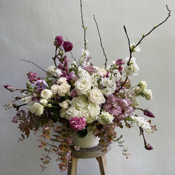 Large floral arrangement with white and pink blooms in a white container