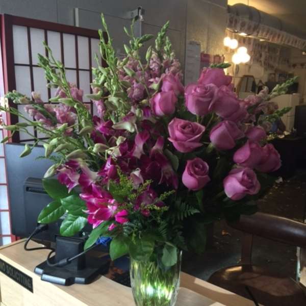 Pink roses and orchids arranged in a clear glass vase