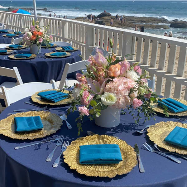 Beachside table setting with a pastel floral centerpiece in a white vase