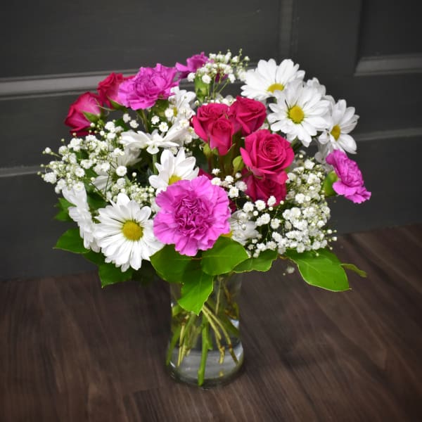 Bouquet of pink roses, white daisies, and pink carnations in a glass vase