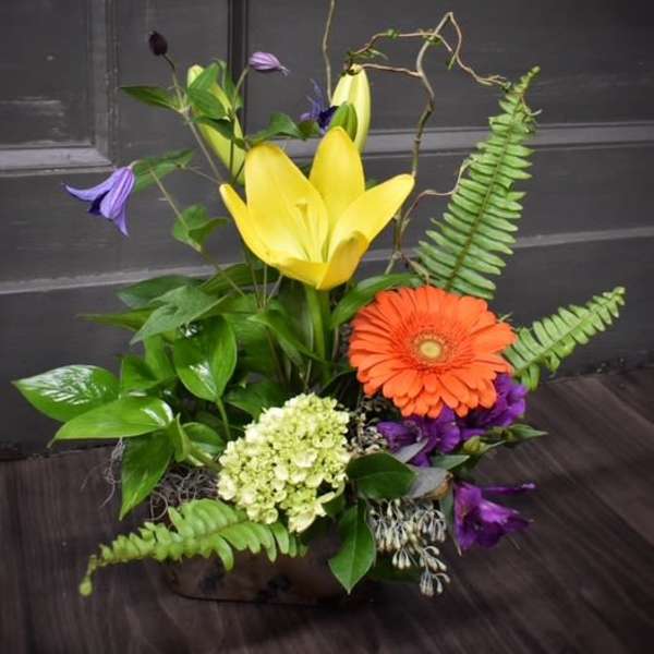 Mixed floral arrangement with yellow lilies and an orange gerbera daisy
