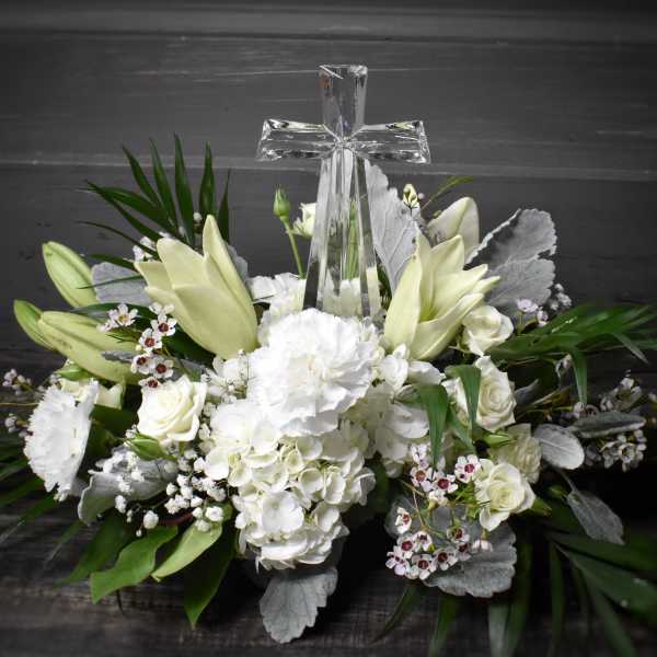 White floral arrangement with a clear glass cross centerpiece