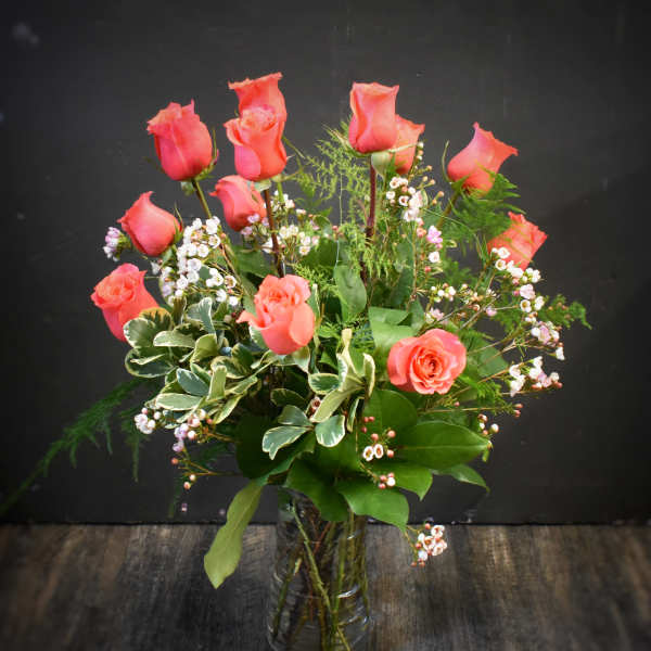 Pink roses arranged in a clear glass vase with small white filler flowers