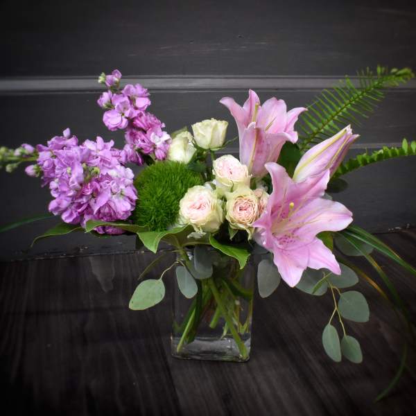 Pink lilies and lavender flowers in a glass vase