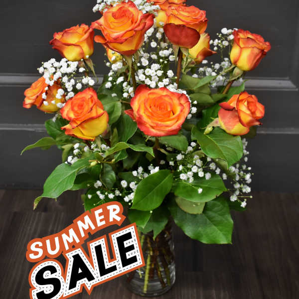 Orange and yellow roses in a glass vase with white filler flowers