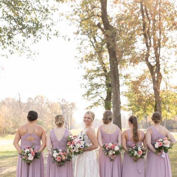 Bride and bridesmaids holding pastel bouquets outdoors