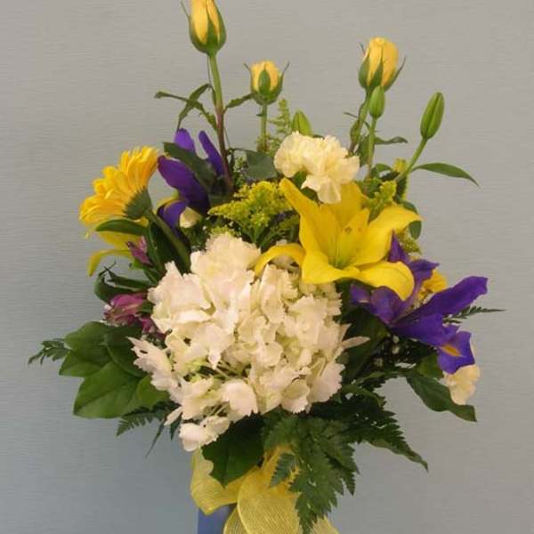 Yellow and purple mixed flower arrangement in a blue vase with a yellow ribbon