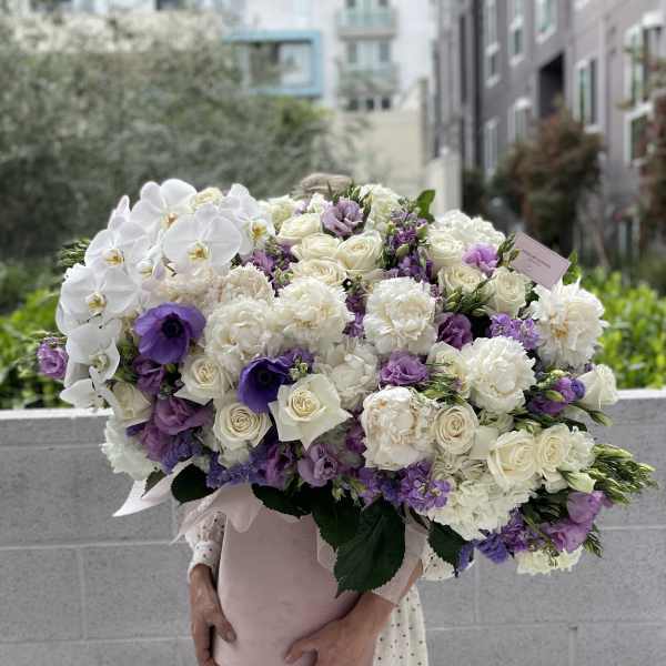 Large bouquet of white and purple flowers wrapped in pink paper