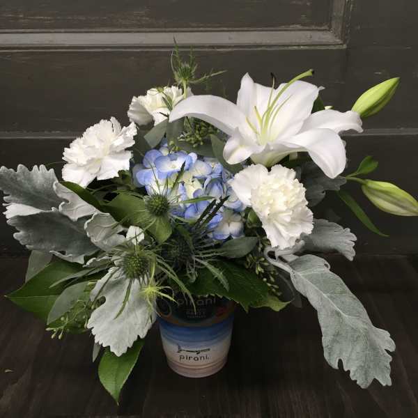 White lilies and carnations with blue hydrangea in a small container