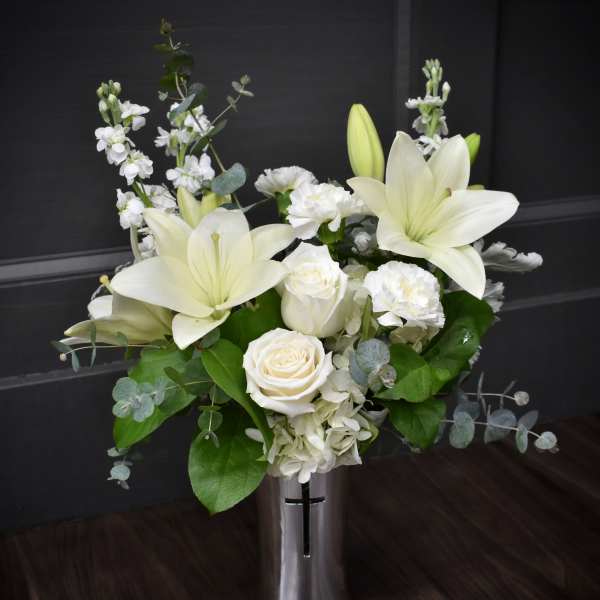 White lilies and roses in a tall silver vase