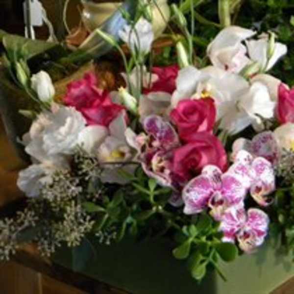 Pink and white floral arrangement in a green container