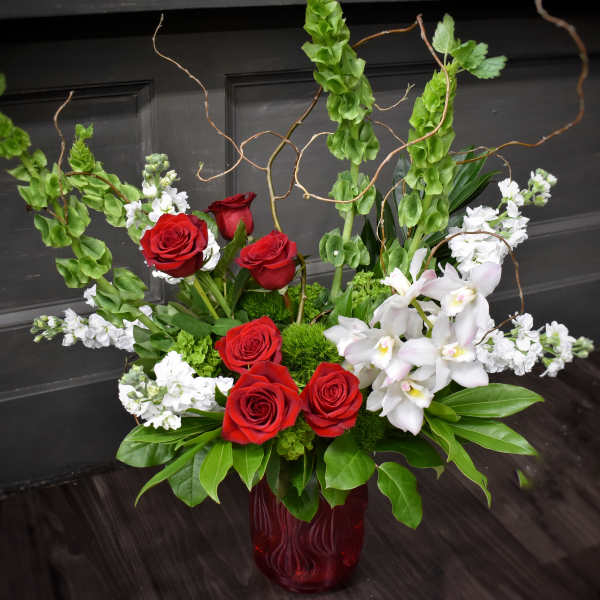 Red roses and white orchids arranged in a red glass vase
