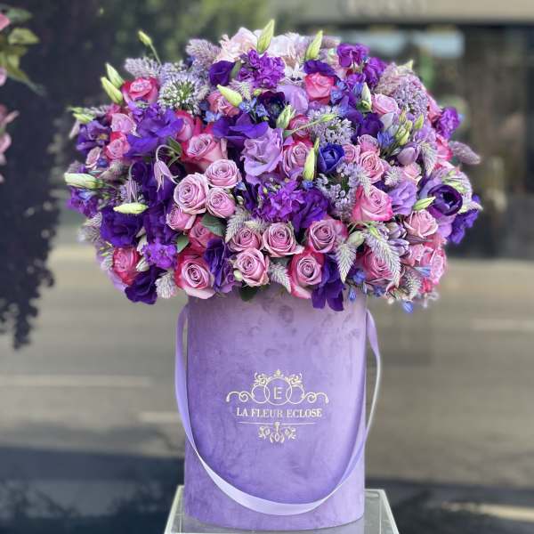 Large bouquet of pink and purple roses in a lavender hatbox