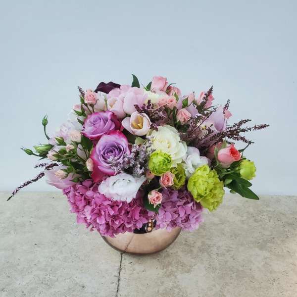 Mixed pink and purple flower arrangement in a round metallic vase