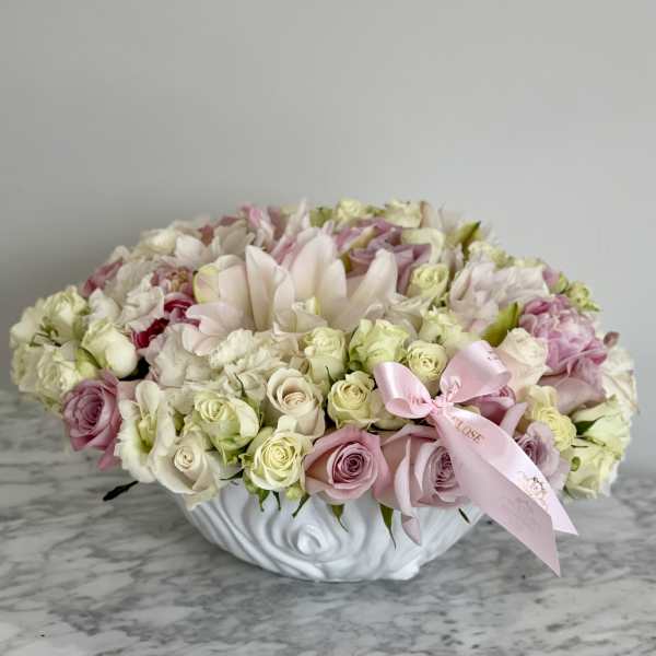 Low floral arrangement of pink and white roses in a white bowl vase