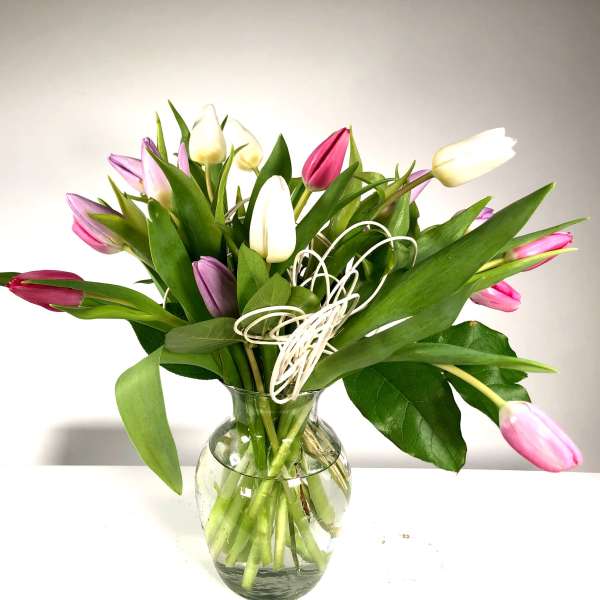 Bouquet of pink, white, and purple tulips in a clear glass vase