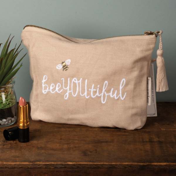 Beige zip pouch with "beeyoutiful" embroidery and a bee motif