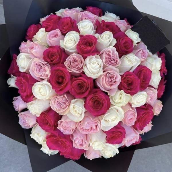 Bouquet of pink, white, and hot pink roses wrapped in black paper