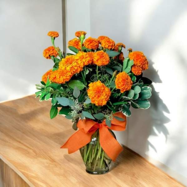Orange marigold bouquet in a glass vase with an orange ribbon