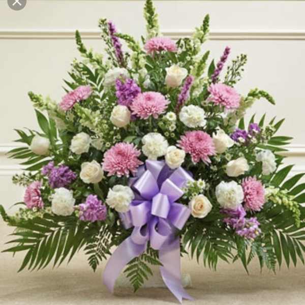 Large pink and white floral arrangement with a purple ribbon bow
