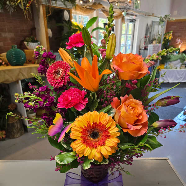 Colorful mixed bouquet in a purple vase with a ribbon