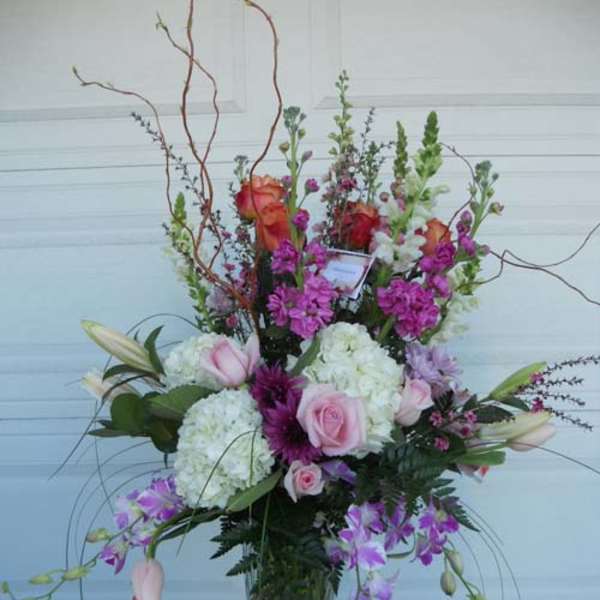 Tall mixed floral arrangement in a glass vase with pink and purple blooms