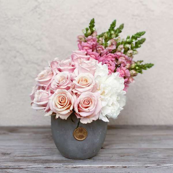Pink and white roses arranged in a gray vase
