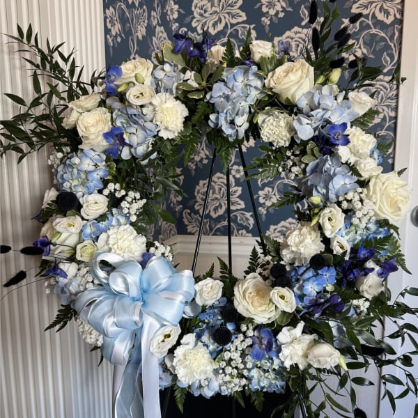 Large floral wreath with white and blue flowers and a pale blue ribbon bow