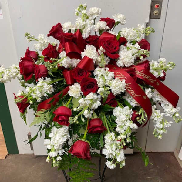 Standing floral spray of red roses and white flowers with red ribbons
