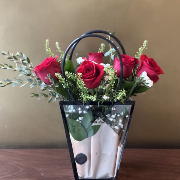 Bouquet of red roses in a black handled gift bag