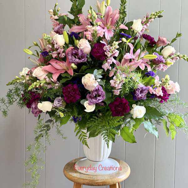 Large mixed bouquet of pink, white, and purple flowers in a white vase