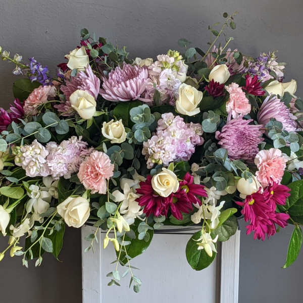 Large pastel floral arrangement with roses, chrysanthemums, and trailing lavender flowers