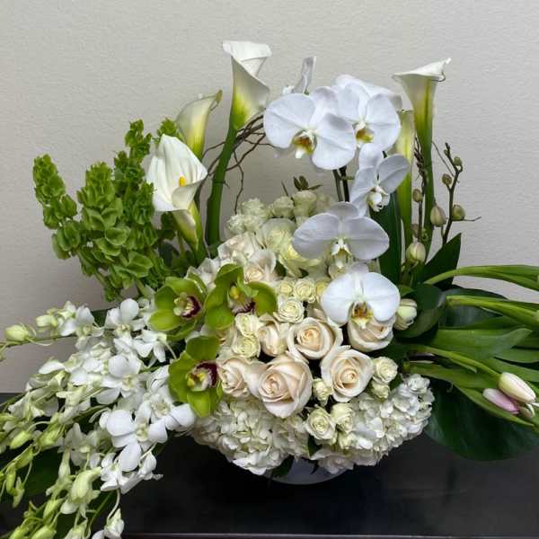 White orchids, calla lilies, roses, and green blooms in a low arrangement