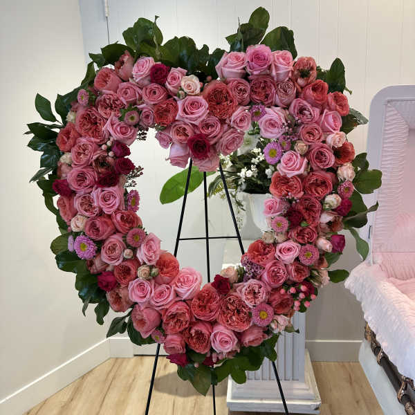 Heart-shaped floral wreath of pink and red roses on a stand