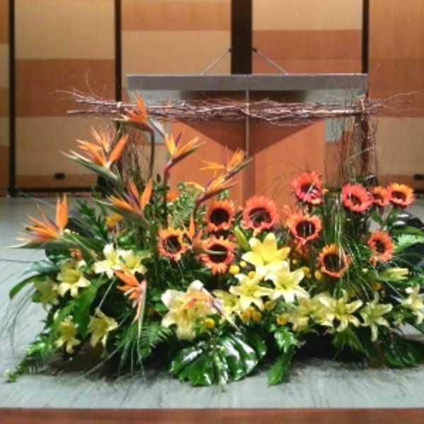 Large orange and yellow tropical flower arrangement displayed in front of a podium