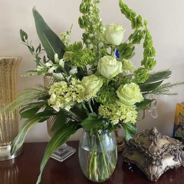 Green and white floral arrangement in a glass vase