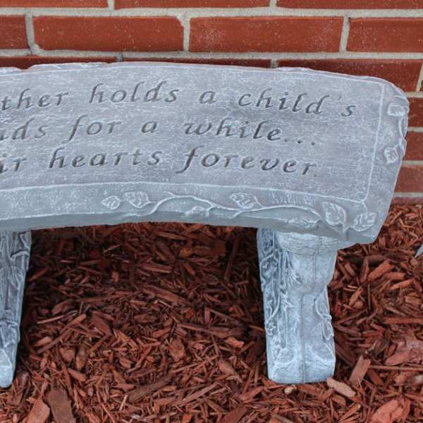Stone bench with an engraved quote in front of a brick wall